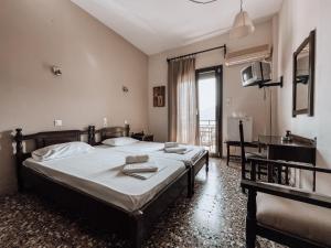 a bedroom with two beds and a desk and a window at Hotel Eleni in Skopelos Town