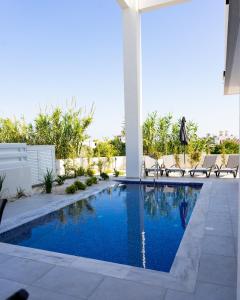 uma piscina num quintal com cadeiras à volta em NISSI 4 Bedroom sea view villa em Agia Napa
