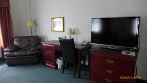 a hotel room with a desk with a television and a chair at The Bridgeport Inn in Fort McMurray