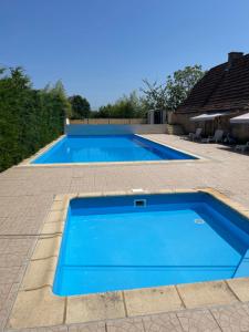 una gran piscina azul en un patio en Mobil-home climatisé, avec 3 chambres et grande terrasse, entièrement équipé, sauf draps en option, pour 6 adultes au maximum, et possibilité de 2 enfants en plus, en Sarlat-la-Canéda