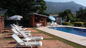 a group of lawn chairs and an infinity pool at Hotel - Pousada 3 Marias in São Pedro