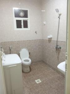 a bathroom with a toilet and a sink and a window at Argaan Apartment in Salalah