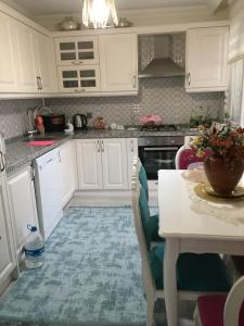 a kitchen with white cabinets and a table at AYDIN APART. in Arsin