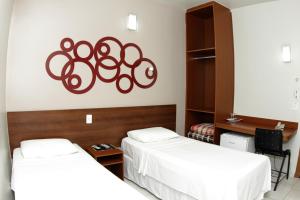 een kamer met twee bedden en een bord aan de muur bij Contagem Centro Hotel in Contagem