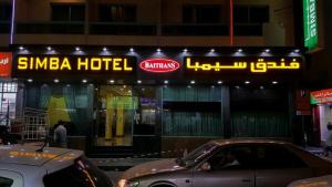 a hotel with a sign and cars parked in front of it at Simba Hotel in Dubai