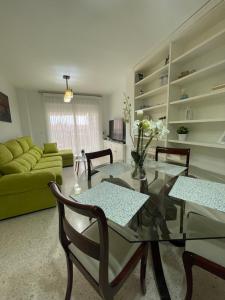 a living room with a glass table and a green couch at ÁTICO BAJO GUÍA in Sanlúcar de Barrameda