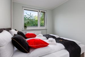 Schlafzimmer mit einem Bett mit roten und schwarzen Kissen in der Unterkunft ApartamentyGdanskEU - Mieszkanie Mewa in Sopot