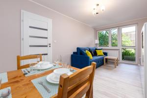 ein Wohnzimmer mit einem blauen Sofa und einem Tisch in der Unterkunft ApartamentyGdanskEU - Mieszkanie Mewa in Sopot