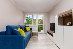 a blue couch with yellow pillows in a living room at ApartamentyGdanskEU - Mieszkanie Mewa in Sopot