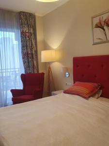 クルジュ・ナポカにあるTraian Residenceのベッドと赤い椅子が備わるホテルルームです。