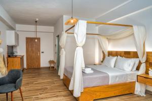 a bedroom with a canopy bed and a chair at Amoudi Studios Apartments Hotel in Amoudi