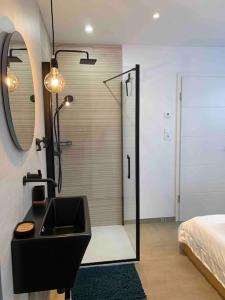 un bagno con lavandino e doccia e un letto di Studio des Charmes 