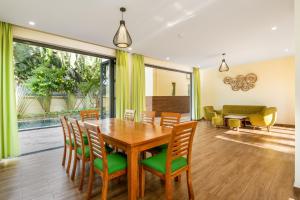 uma sala de jantar com uma mesa de madeira e cadeiras em Co Villas em Hoi An