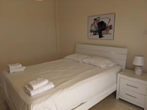 a bedroom with a white bed with towels on it at Adalena Court in Paralimni