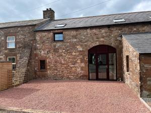 - une vue extérieure sur un bâtiment en briques avec un garage dans l'établissement The Cottage, à Carlisle