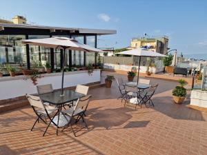 拿坡里的住宿－La terrazza delle fate，屋顶上带桌椅和遮阳伞的天井