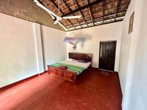 1 dormitorio con 1 cama y ventilador de techo en Lake House Homestay, en Anuradhapura