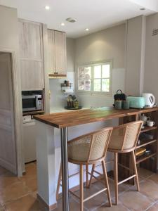 a kitchen with a wooden counter and two chairs at Le Jas du Romarin in Callas