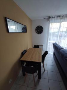 uma sala de jantar com uma mesa e um relógio na parede em Agde Studio proche Plage em Agde