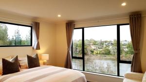 a bedroom with a bed and large windows at Wonderful River View-Brand New Home - 4 Bedrooms in Hamilton