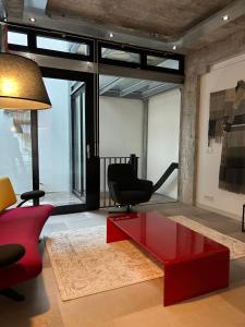 - un salon avec une table basse rouge et une chaise dans l'établissement De Eindhovenaar City Apartments, à Eindhoven