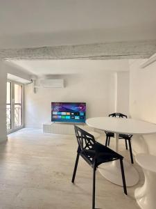Habitación blanca con mesa, sillas y TV. en Nouveau - Nice Mamac - centre en Niza