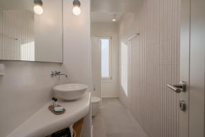 a white bathroom with a sink and a shower at Castello Amorgos Suites in Katapola +88 photos