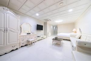 Donghae Medical Spa Convention Hotel في دونغ هاي: غرفة نوم بيضاء كبيرة مع سرير وأريكة