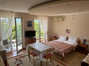 una camera con letto, tavolo e TV di Villa Alla Bed and Breakfast a Herceg-Novi