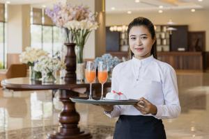 une femme tenant un plateau avec deux verres de vin dans l'établissement Otres Beach Hotel, à Sihanoukville