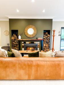 a brown couch in a living room with a fireplace at Hamilton House - Snowy Mountain Luxury Villas in Jindabyne