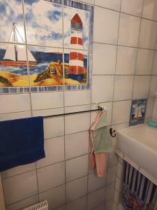 baño con una pintura de un faro en la pared en Haus-Crone, en Burgtiefe auf Fehmarn 