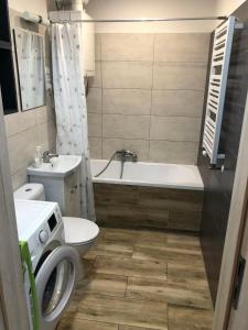 a bathroom with a tub and a toilet and a sink at Apartament Zwirki i Wigury 38 in Bydgoszcz