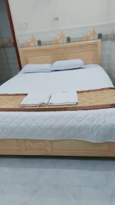 ein Holzbett mit weißer Bettwäsche und Kissen darauf in der Unterkunft MOTEL THỦY TIÊN in Vũng Tàu