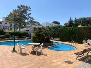 un patio con mesa y sillas junto a una piscina en Precioso apartamento con piscina, en Castelldefels