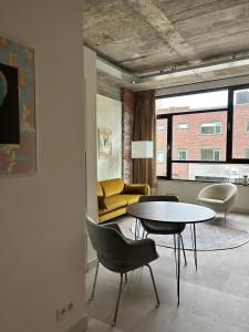 een woonkamer met een tafel en stoelen en een bank bij De Eindhovenaar City Apartments in Eindhoven