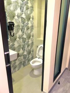 a bathroom with a toilet and a green and white wallpaper at Nona Hotel, Bangkok in Makkasan