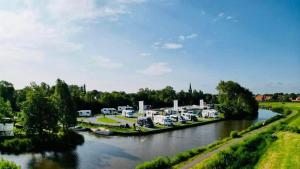 a river with a bunch of rvs parked on the side at Tiny house aan het water op de appelhof in Wommels