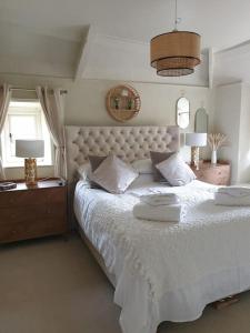 um quarto com uma grande cama branca e 2 candeeiros em Rosedale a charming detached 4 bedroom cottage. em Brixham