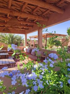 a patio with a couch and some blue flowers at Maison d'hôtes Tigminou - Adults Only in Aït Benhaddou