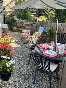 uma mesa preta e cadeiras com um guarda-sol e flores em Rosedale a charming detached 4 bedroom cottage. em Brixham