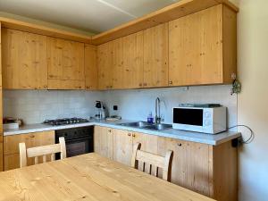 a kitchen with wooden cabinets and a table with a microwave at Chalet Ceppo in Bormio