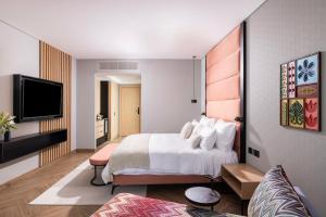 a hotel room with a bed and a flat screen tv at Almond Hotel - Adults only in Neve Ilan