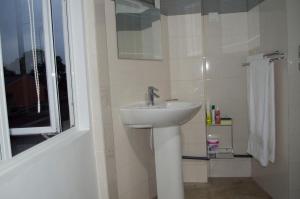 a white bathroom with a sink and a shower at Paramount Residence 5 in Peliyagoda