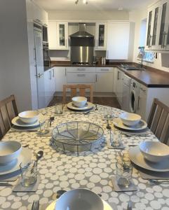 a kitchen with a table with plates and bowls on it at Glasfor by the beach at Trearddur Bay in Trearddur