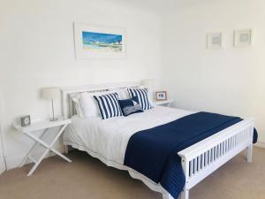 a white bedroom with a bed with blue and white pillows at Glasfor by the beach at Trearddur Bay in Trearddur