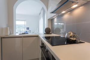 a kitchen with white cabinets and a tea kettle on the counter at Villa AMICA in Zaton +23 photos