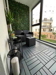 eine Terrasse mit einer grünen Wand sowie einem Tisch und Stühlen in der Unterkunft Appartement avec son jardin d’hiver in Poissy
