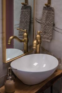 a bathroom with a white sink and gold faucet at Athina's little apartment in Thessaloniki
