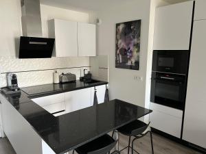 cocina con encimera negra y armarios blancos en Appartement avec son jardin d’hiver en Poissy